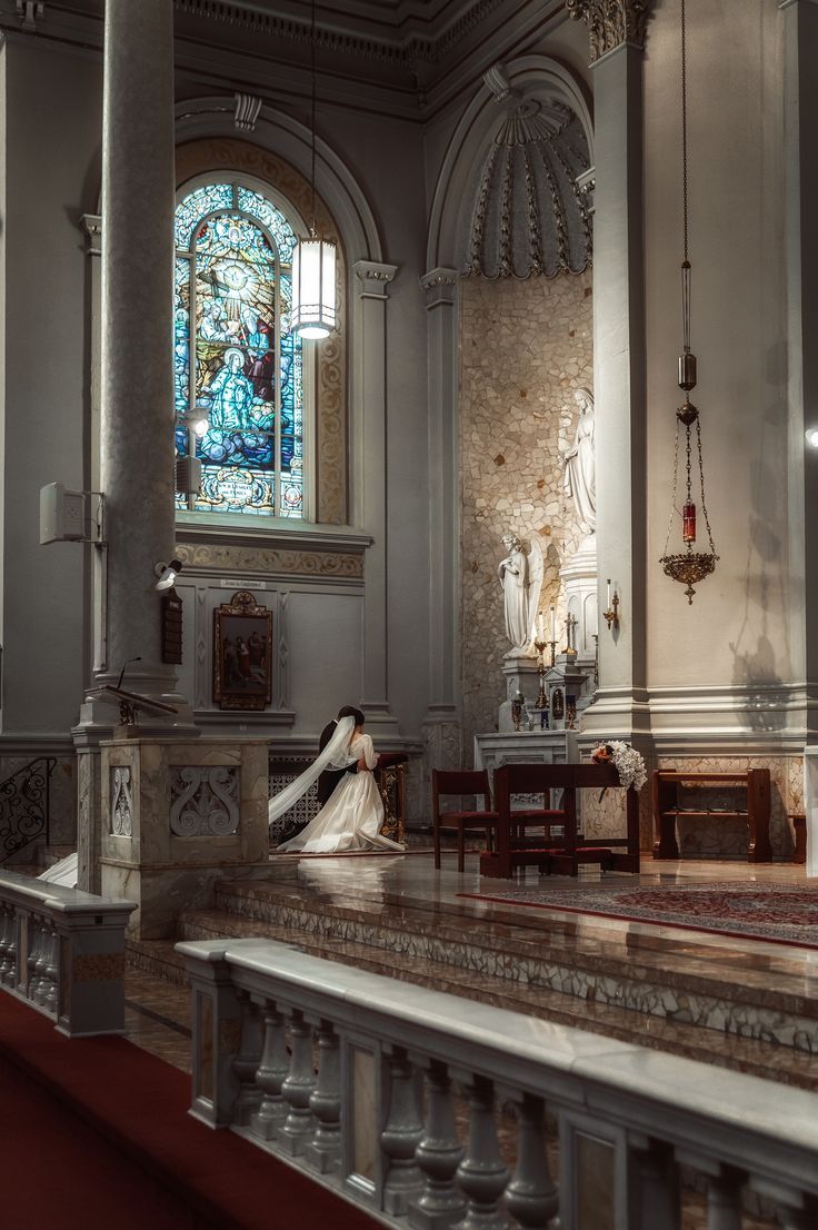 a woman sitting on the floor in front of a stained glass window at a church