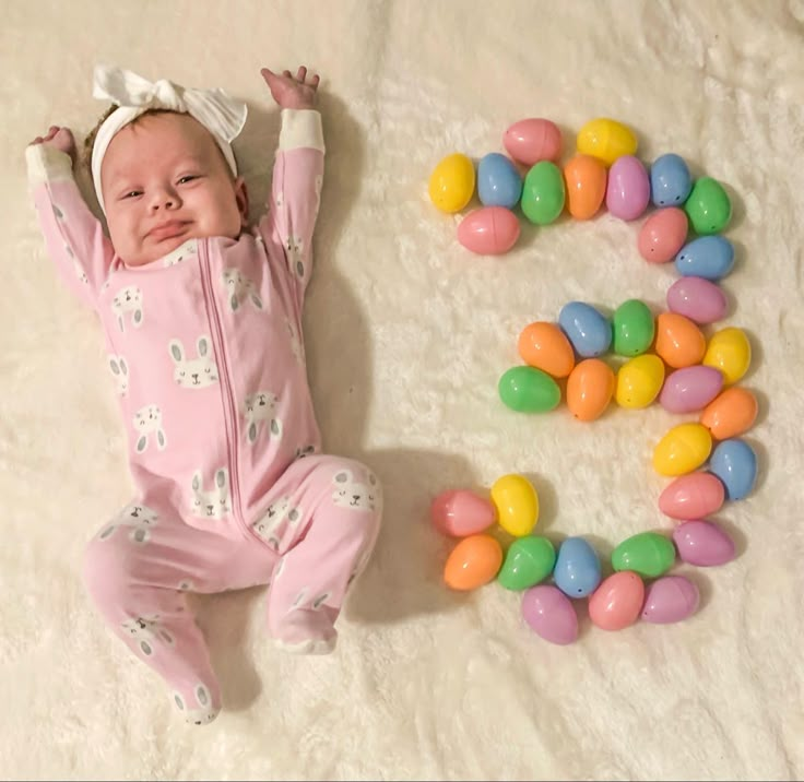 a baby laying on its back next to the letters e and m made out of candy