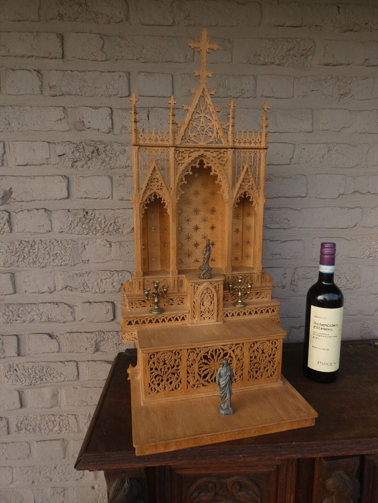 a bottle of wine sitting on top of a table next to a wooden structure with carvings