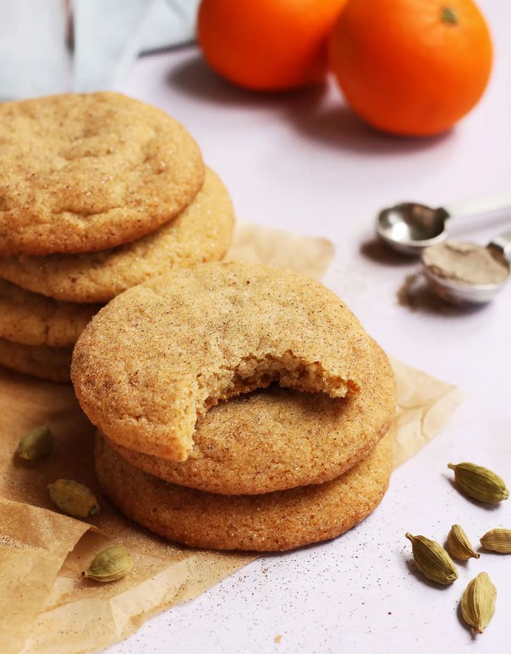 three cookies are stacked on top of each other with two oranges in the background