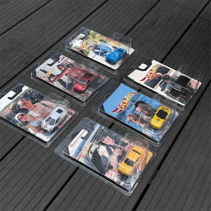 four plastic trays with cars in them on a wooden table, one has a yellow car and the other is blue