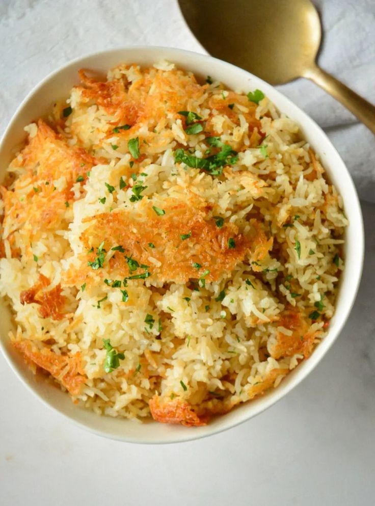 a white bowl filled with rice and meat covered in parmesan sprinkles