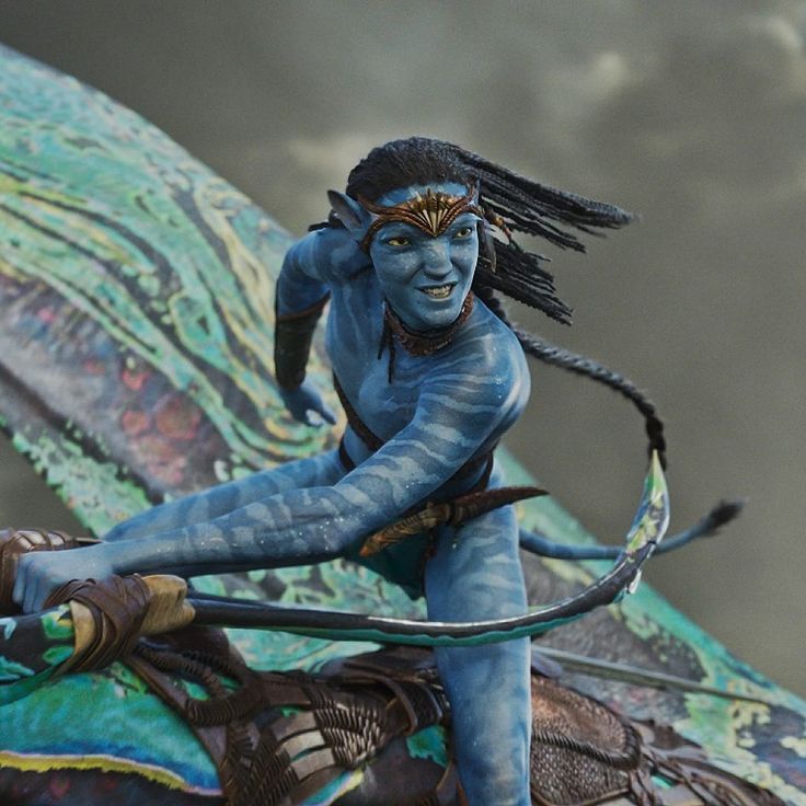 a statue of a man with blue skin and black hair holding a bow on top of a dragon