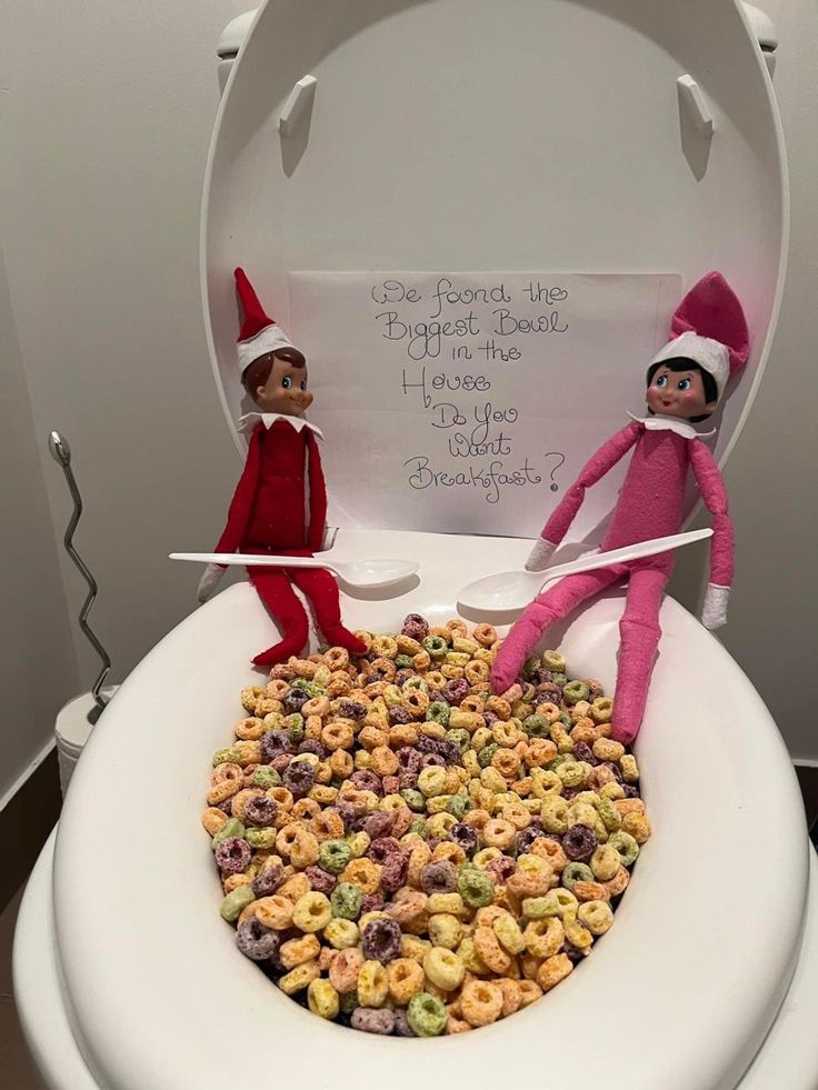 two elfs sitting on top of a toilet bowl filled with cereal