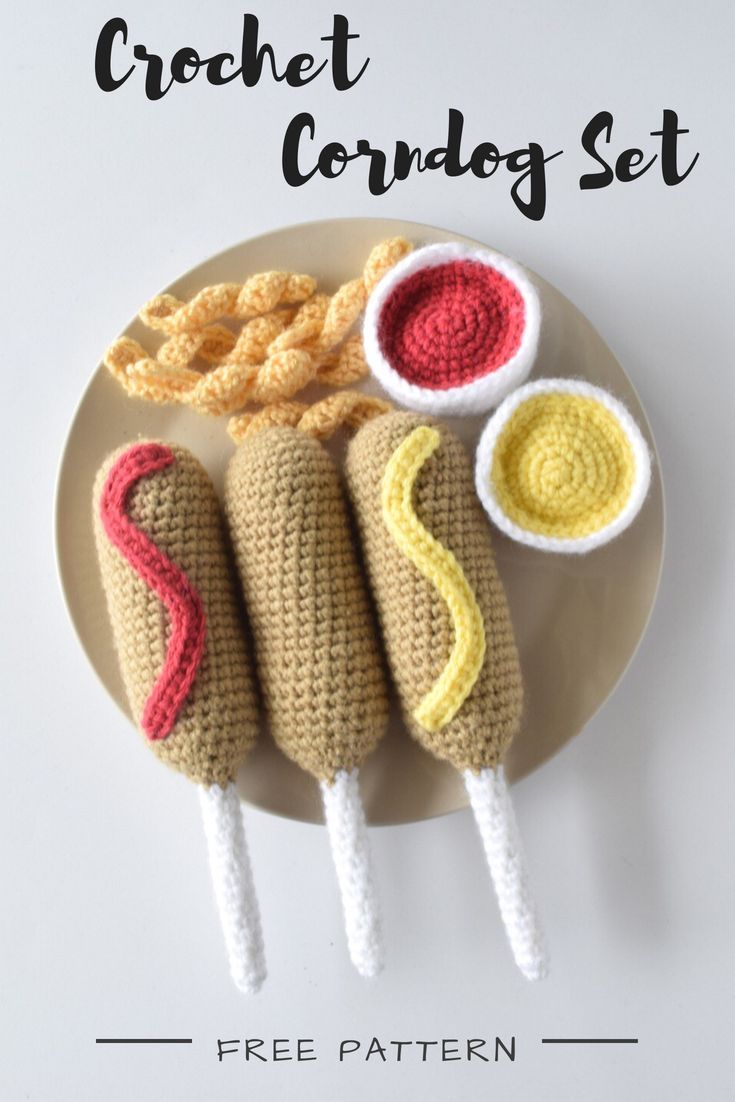 three crochet hot dogs on a plate with dipping sauces