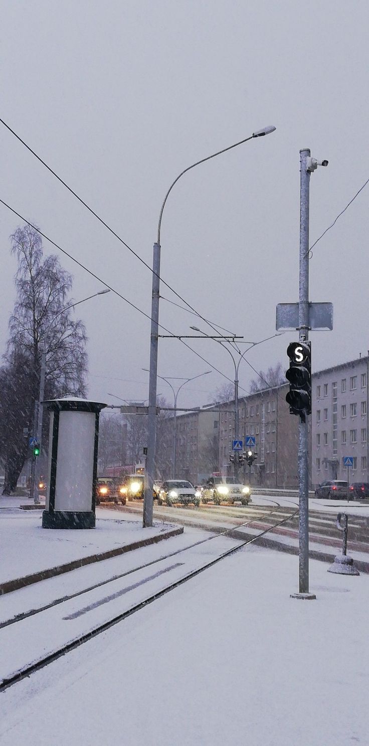 traffic lights and street signs on a snowy day with buildings in the backgroud