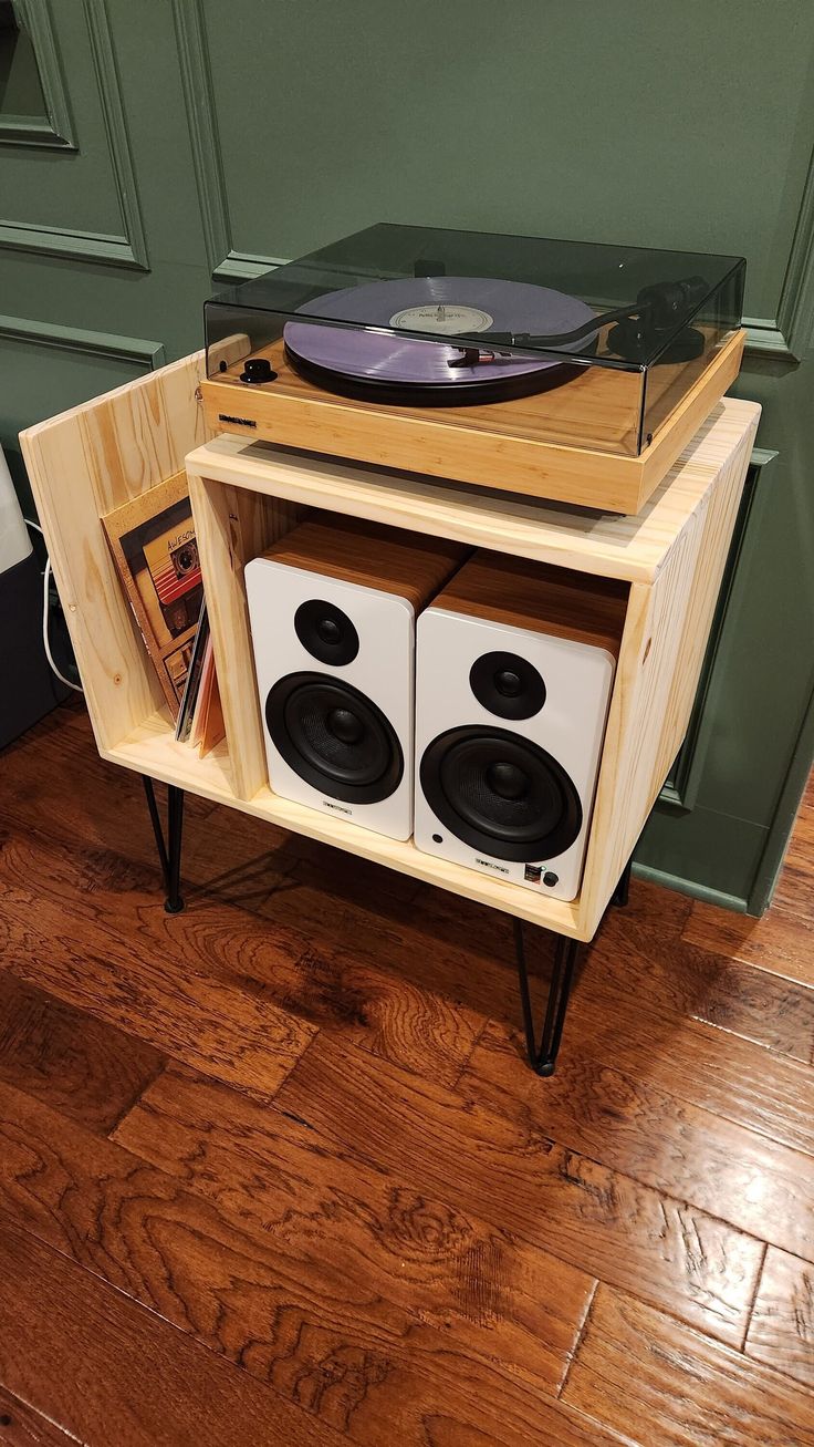 an old record player is sitting on top of a wooden stand with speakers and records