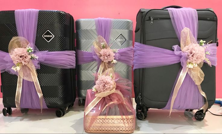 three pieces of luggage wrapped in purple and gold ribbons with bows on them, sitting next to each other