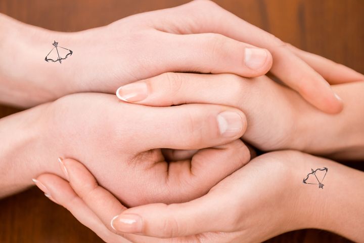 two hands holding each other with small tattoos on their wrists and fingers above the palms