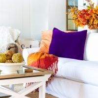 a living room filled with white furniture and colorful pillows