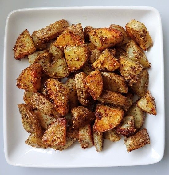 a white plate topped with fried potatoes on top of a table