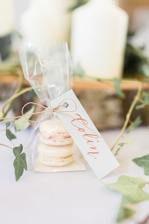 a small bag filled with macaroons sitting on top of a table next to candles