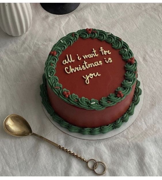 a red and green christmas cake on a white tablecloth with a spoon next to it