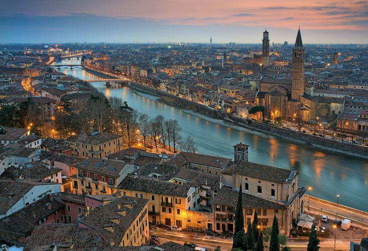 an aerial view of a city at night with lights on the buildings and river running through it