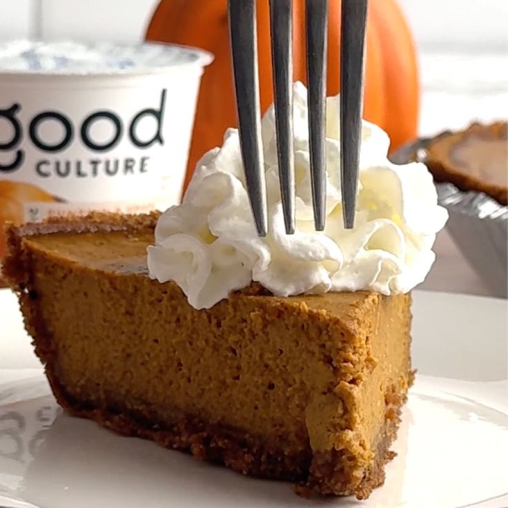 a slice of pumpkin pie with whipped cream on top and a fork stuck in it