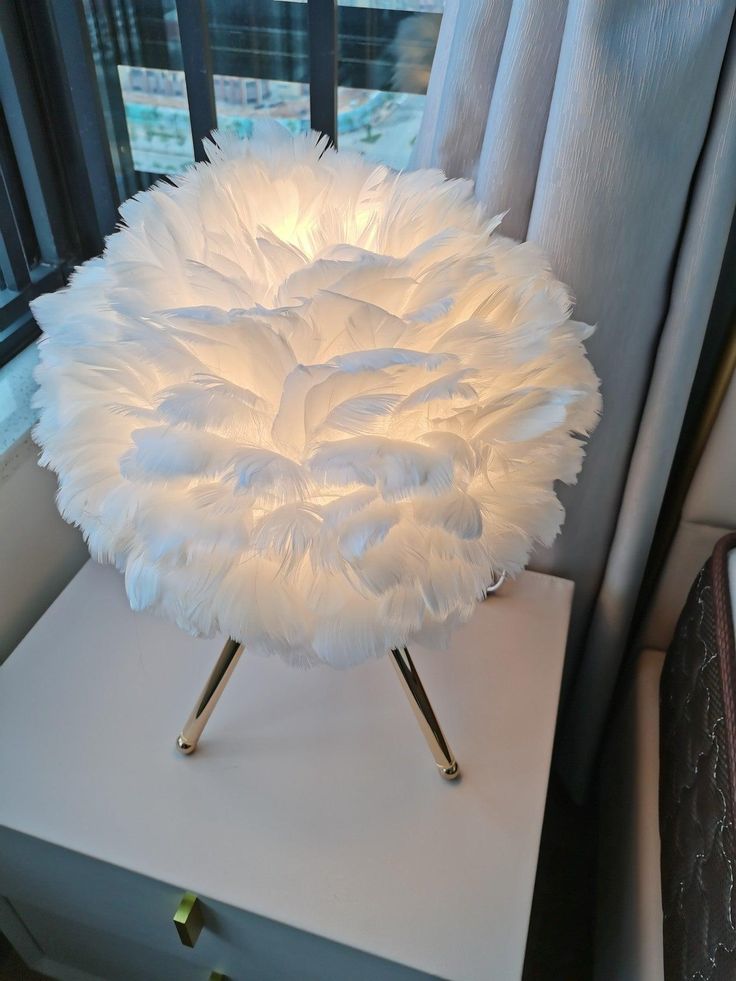 a white lamp sitting on top of a table next to a window