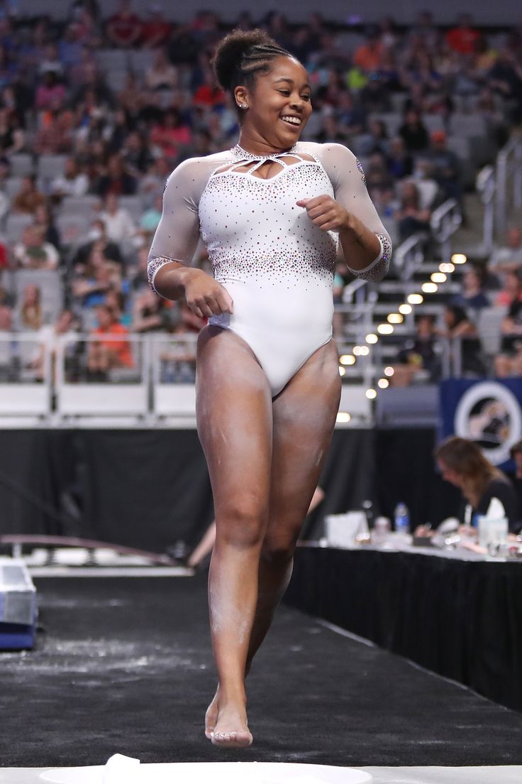 a woman standing on top of a stage wearing a white bodysuit and smiling at the camera