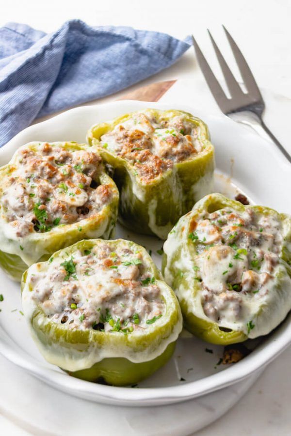 several stuffed peppers on a white plate with a fork and napkin next to it,