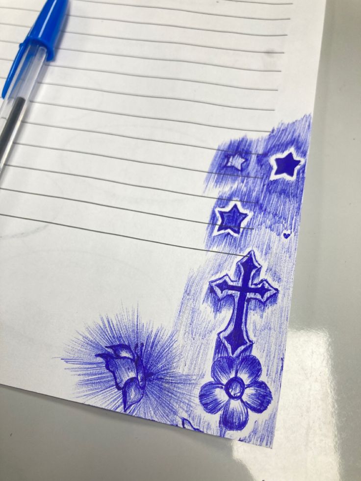 a blue pen is sitting on top of a piece of paper that has an image of a cross and flowers