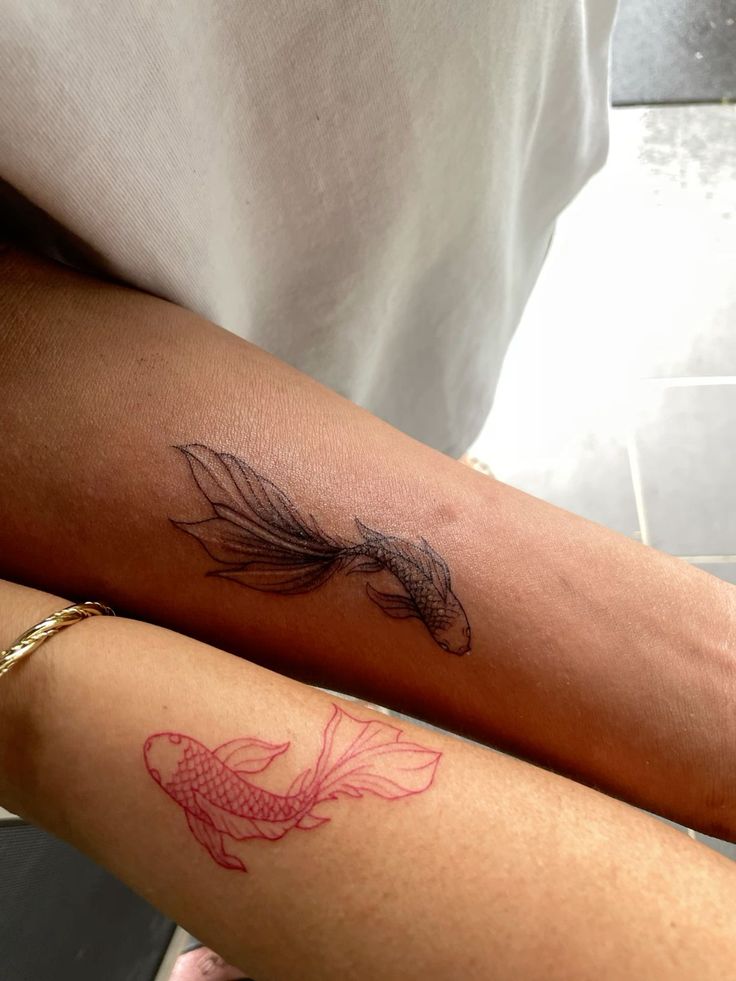 two people with tattoos on their arms, one has a fish and the other has a goldfish