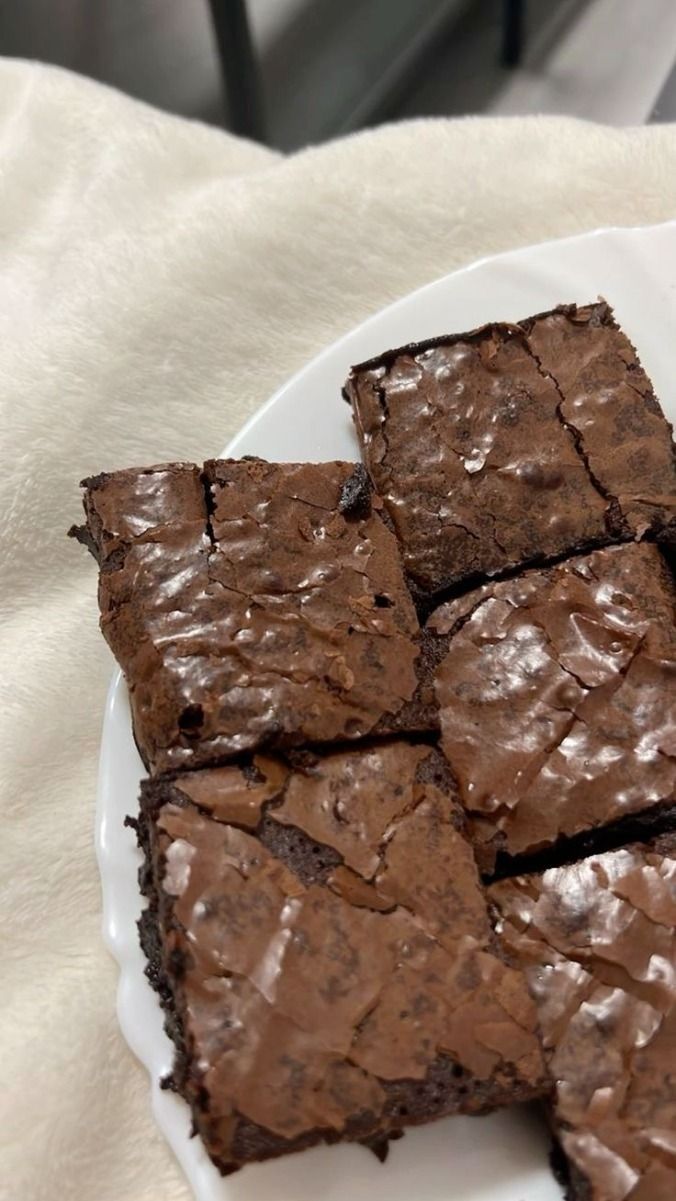 chocolate brownies on a white plate sitting on top of a table next to a napkin