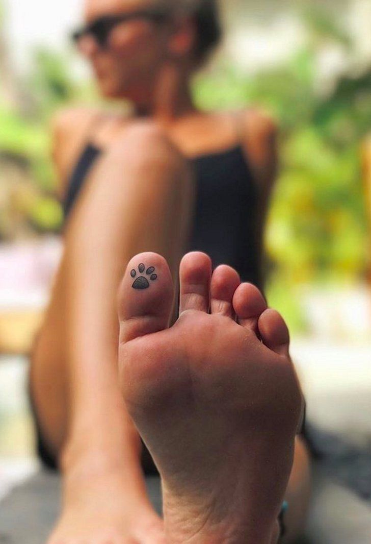 a person with a paw tattoo on their foot sitting in front of a woman's legs