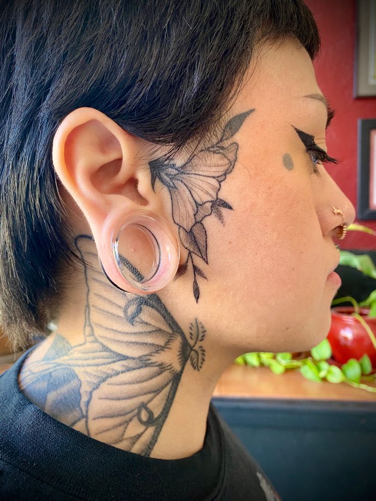 a woman with tattoos on her neck and behind the ear