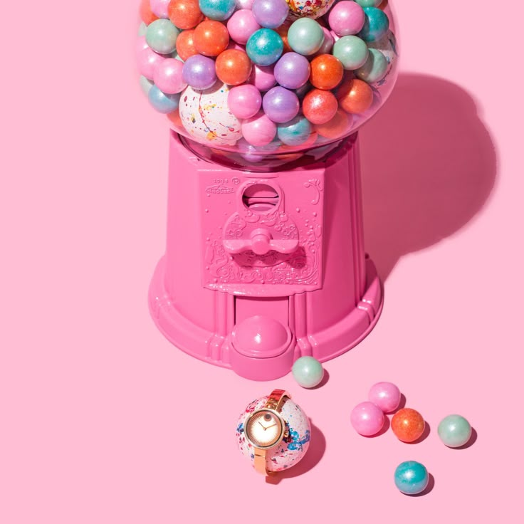 a pink gummy machine filled with lots of colorful candies on top of a pink background