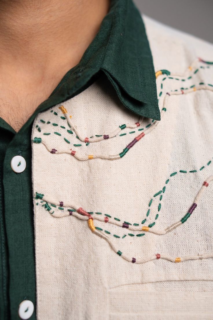 a close up of a person wearing a green shirt with beads on the collar and chest