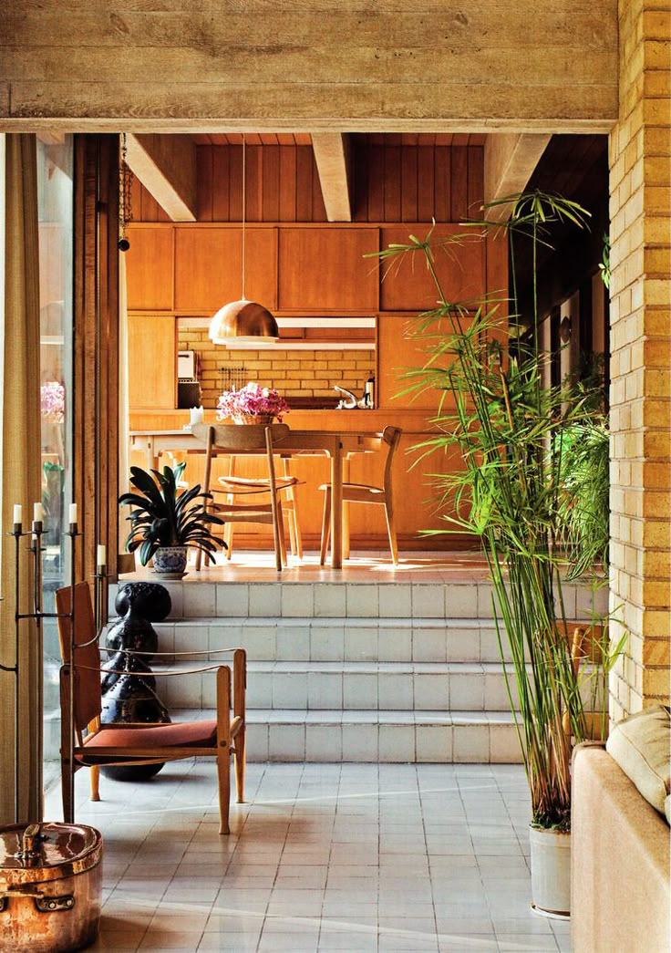 an open door leading to a kitchen and dining area with potted plants on the steps