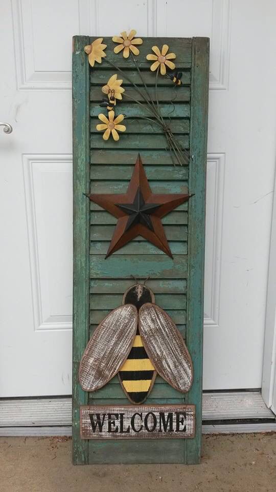 a welcome sign with flowers and a bee on it in front of a white door