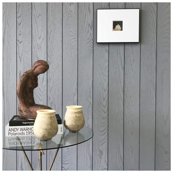 a glass table topped with two vases next to a wall mounted photo on a wooden paneled wall