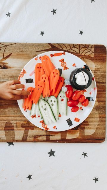 a person is cutting carrots on a white plate with black writing and stars in the background