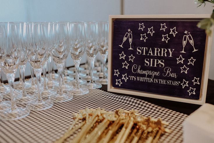 there are many wine glasses on the table and one has a sign that says starr sips champagne day