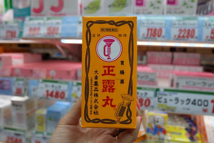 a person holding up a yellow box with chinese writing on it in front of some shelves