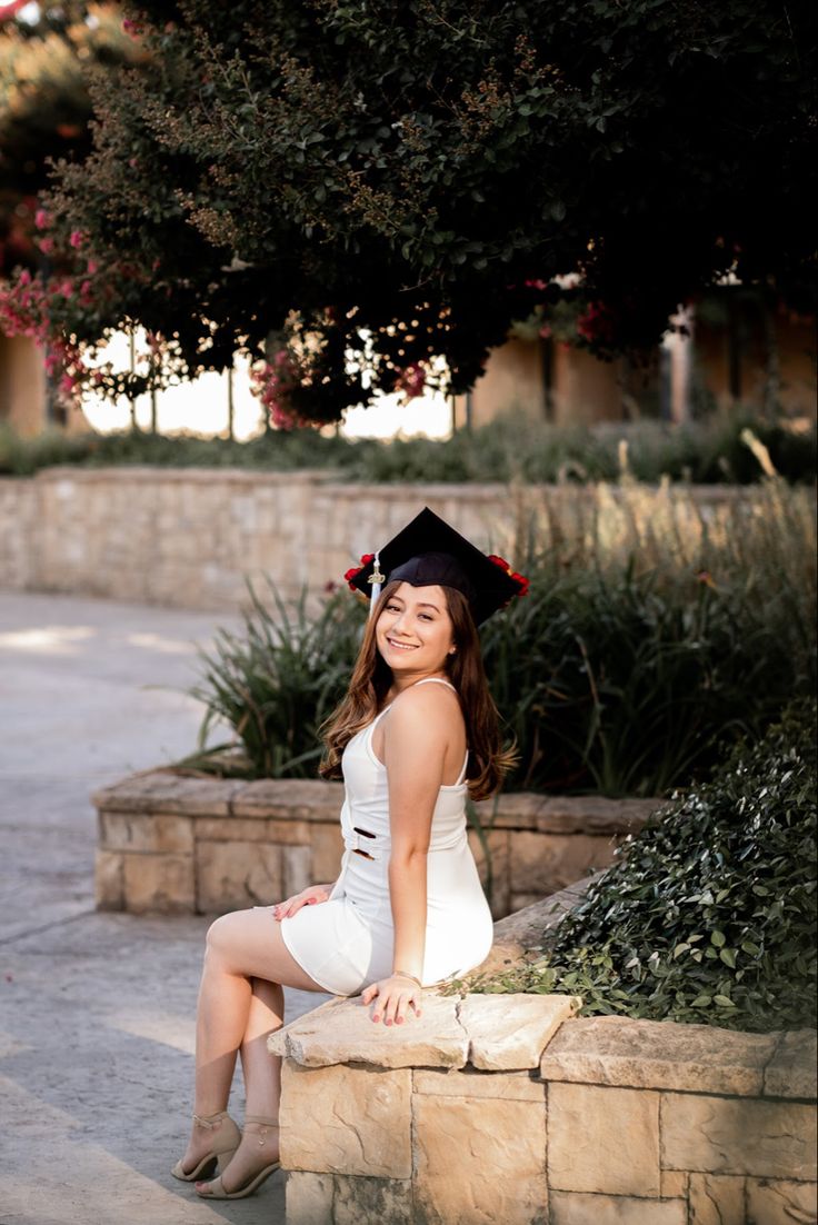 a woman in a graduation cap sitting on a stone bench