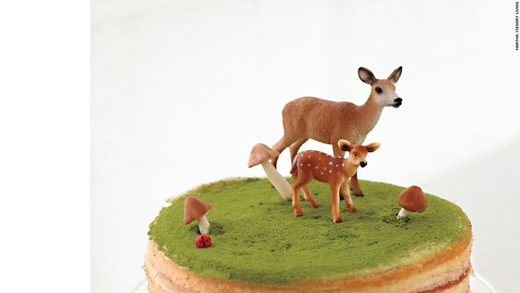 a cake with green frosting and two deer figurines sitting on top of it