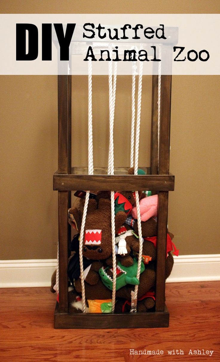 a stuffed animal in a wooden cage with rope hanging from it's sides on the floor