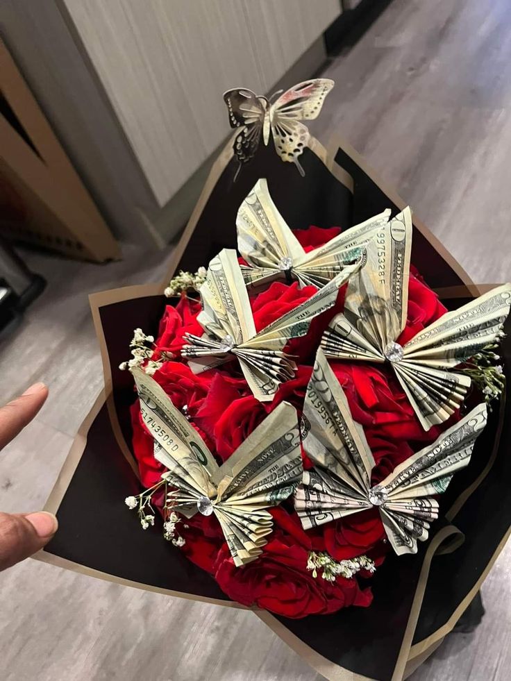 a bouquet of red roses and dollar bills in the shape of butterflies