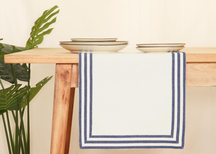 two plates on top of a wooden table next to a potted plant and a white wall