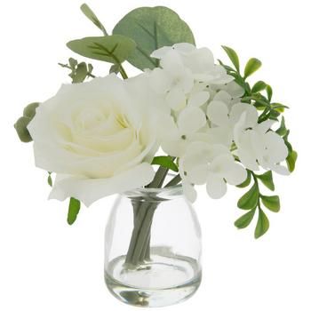 white flowers in a clear glass vase on a white background with green leaves and stems