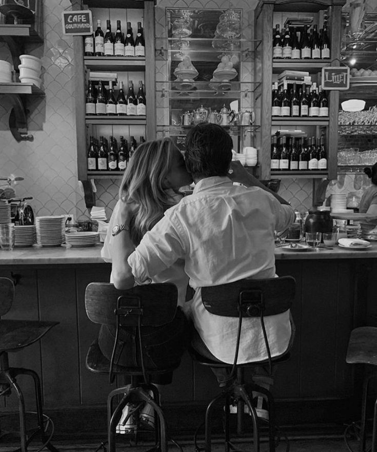 a man and woman sitting at a bar kissing