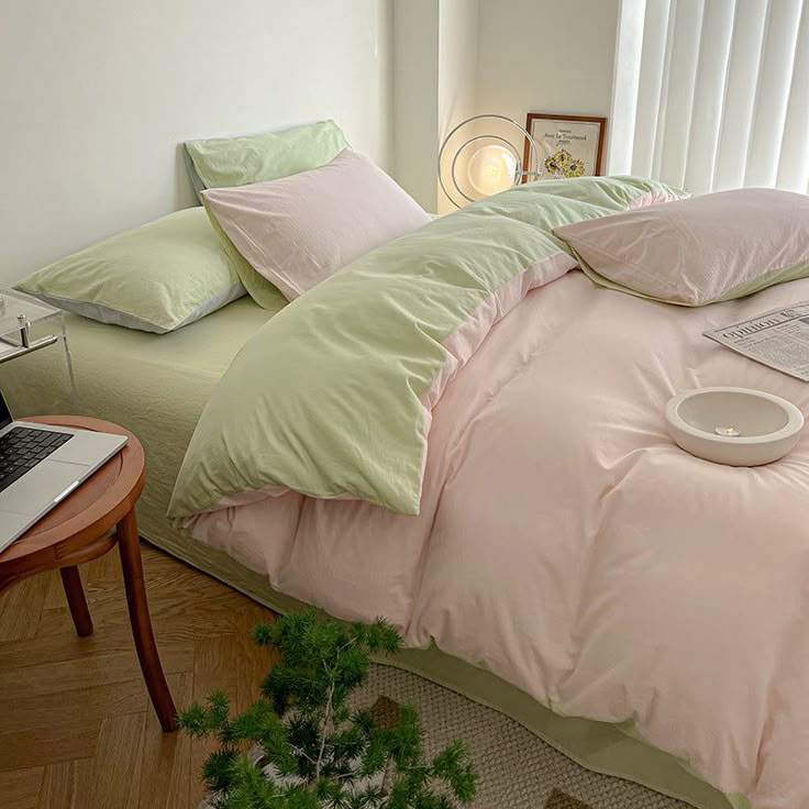 a laptop computer sitting on top of a bed in a bedroom next to pillows and blankets