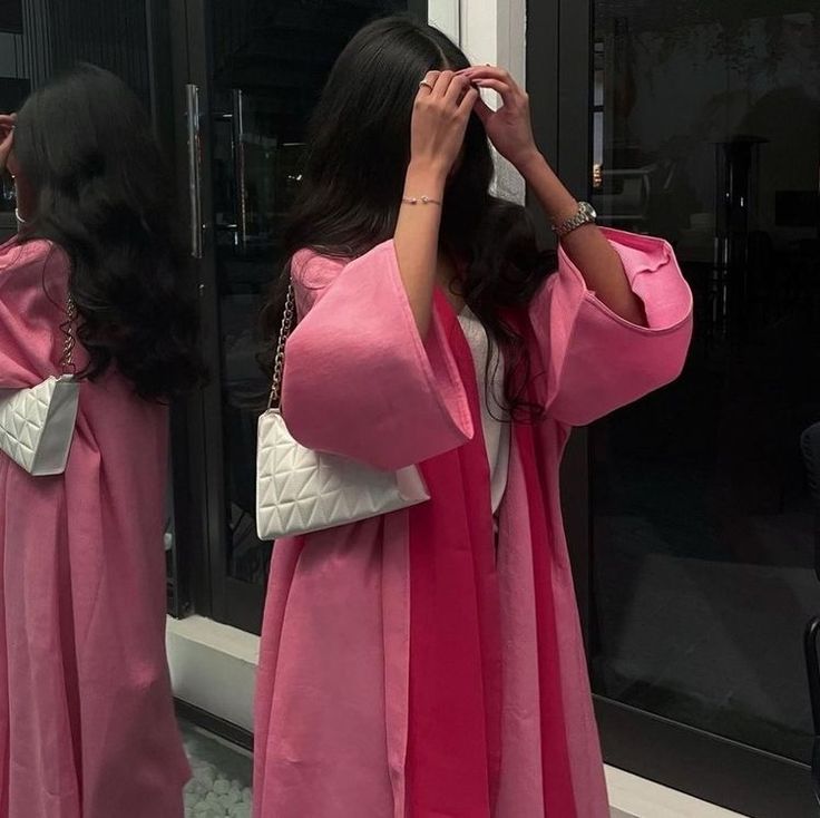 a woman in a pink robe looking into a mirror