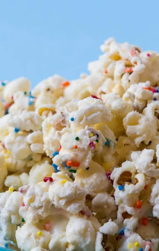 white popcorn with sprinkles and multicolored candies in a blue bowl