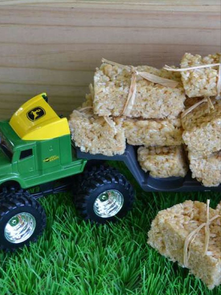 a toy truck filled with rice krispy treats on top of green grass next to a wooden box