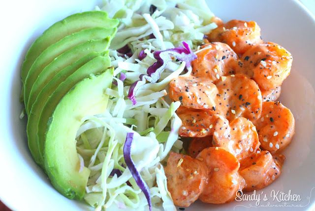 a white bowl filled with shrimp and coleslaw next to an avocado