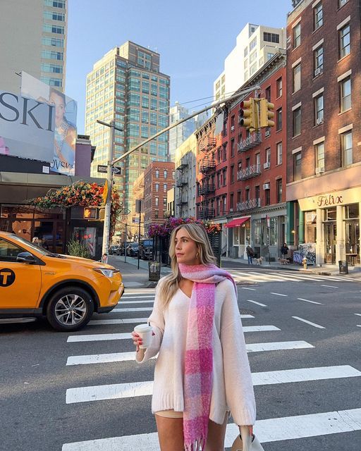 a woman is crossing the street wearing a scarf