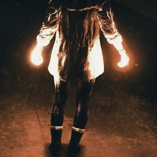 a woman standing in the dark holding torches