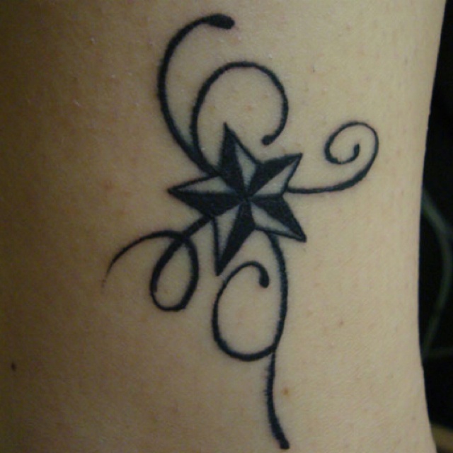 a black and white tattoo design on the side of a woman's leg with swirls